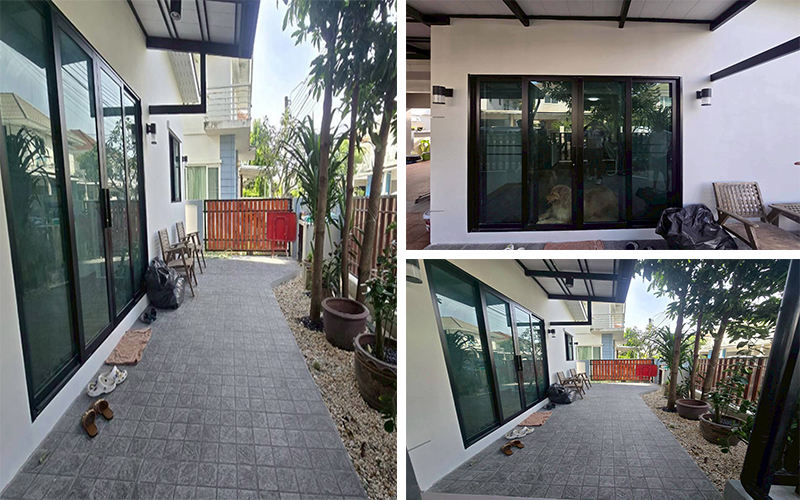 บานเลื่อนอลูมิเนียมกระจกดำทั้งแนว พื้นกระเบื้องสีเทา และทางเดินหินกรวดตกแต่ง